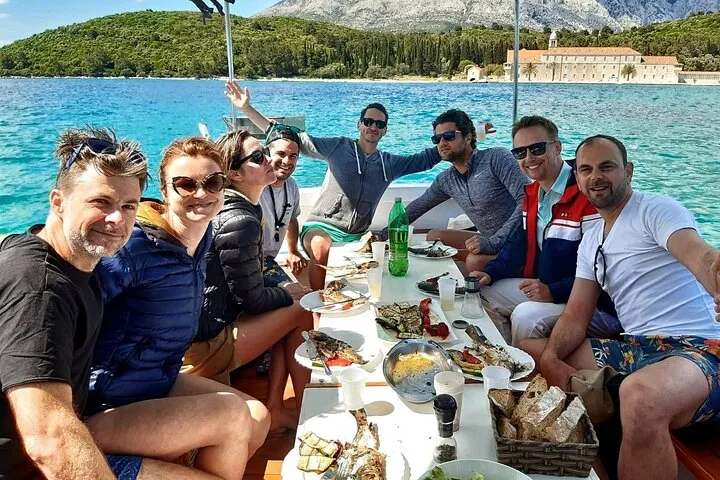 Small white boat anchored in a turquoise bay of the Korcula archipelago on the Fish and Fun swim and grill boat tour from Korcula Town in Croatia